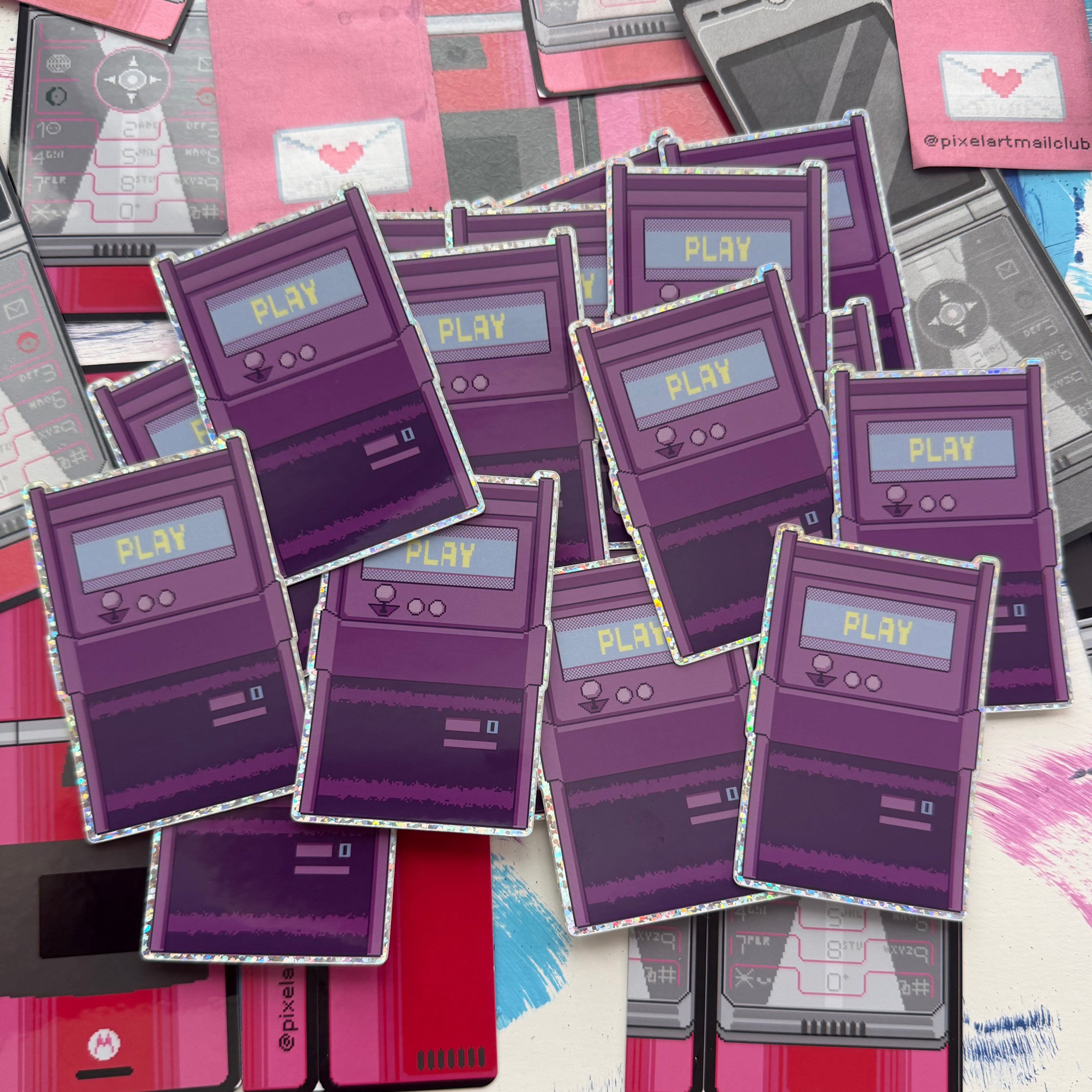 A pile of die-cut stickers shaped like retro purple arcade cabinets, scattered over a background collage of similar cassette and smartphone illustrations.